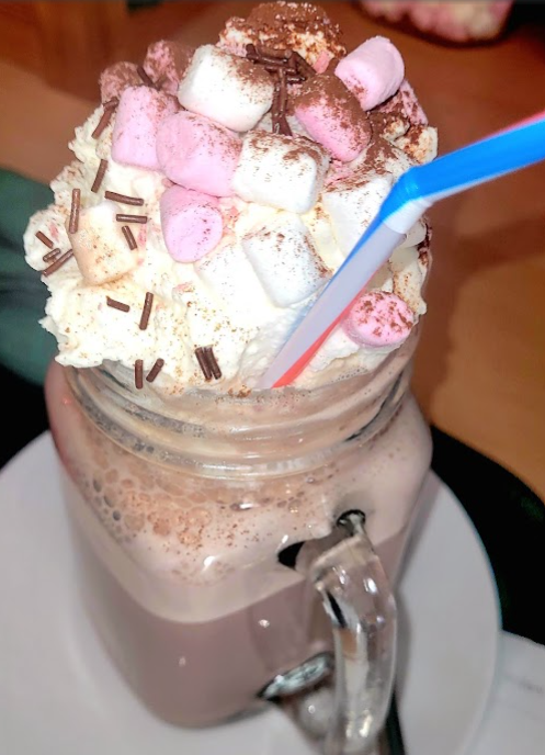 Hot chocolate topped with cream, marshmallows and sprinkles